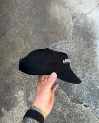 Cassowary Drive Short Brim Logo Hat — side view showing woven logo patch